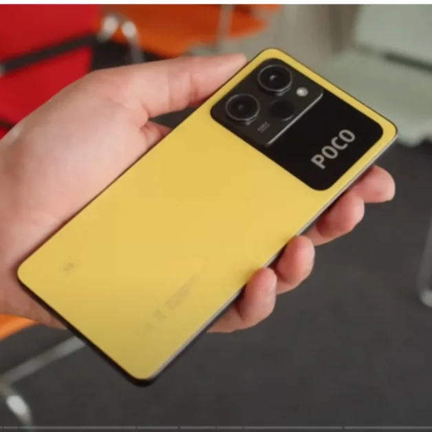 Hand holding yellow Poco X5 Pro smartphone with dual camera setup.