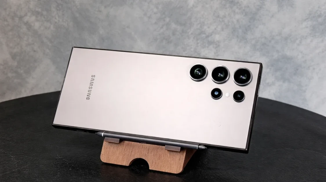 Samsung Galaxy S23 Ultra placed horizontally on a wooden stand with camera lenses visible in a clean studio setting