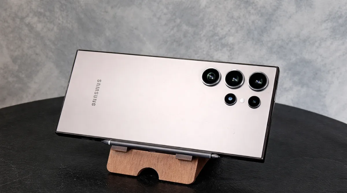 Samsung Galaxy S23 Ultra placed horizontally on a wooden stand with camera lenses visible in a clean studio setting