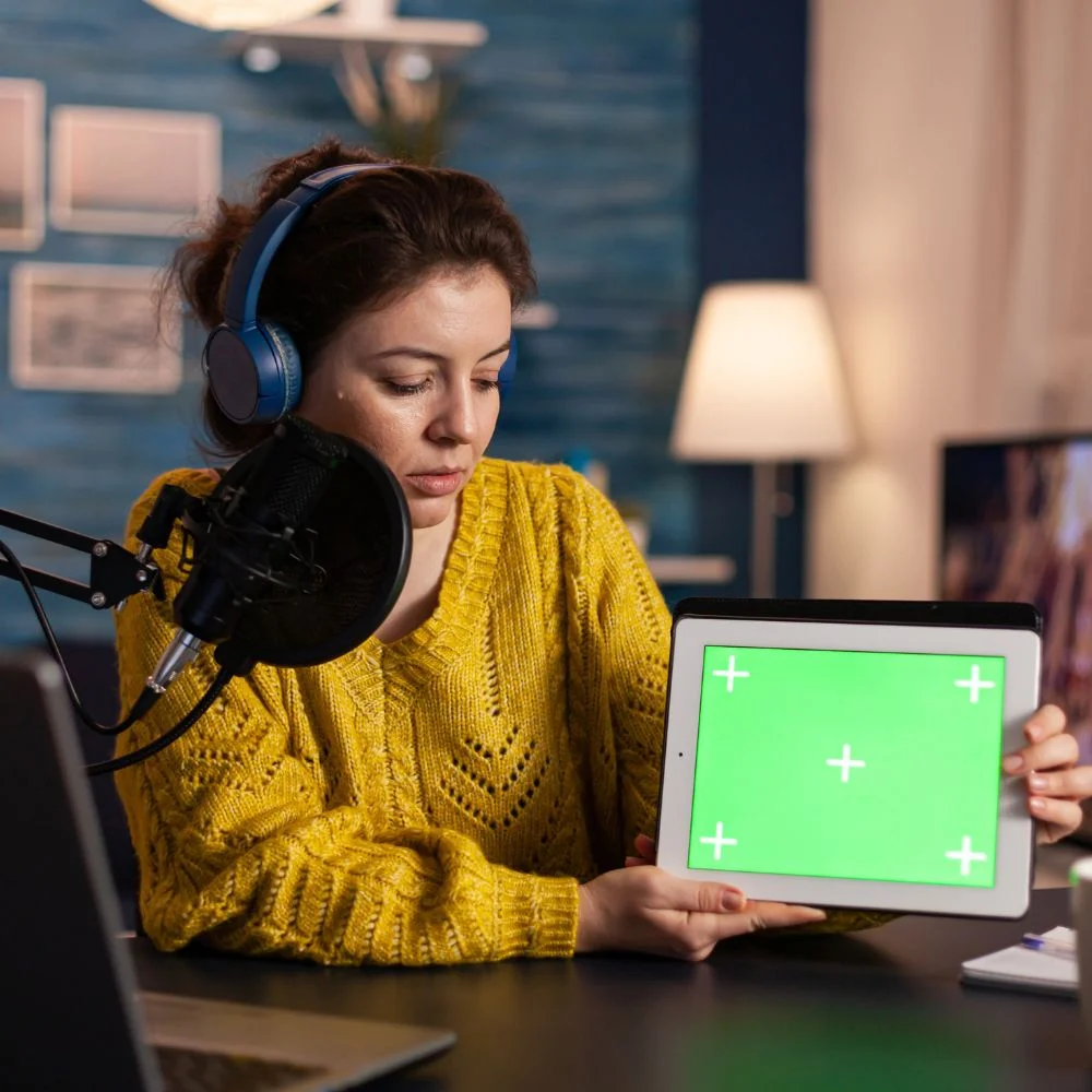 vlogger-looking-laptop talking about tablet with chroma key desktop